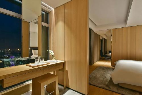 a room with a bed and a desk with a window at THE AMNIS, a Luxury Collection Hotel, Kaohsiung in Kaohsiung