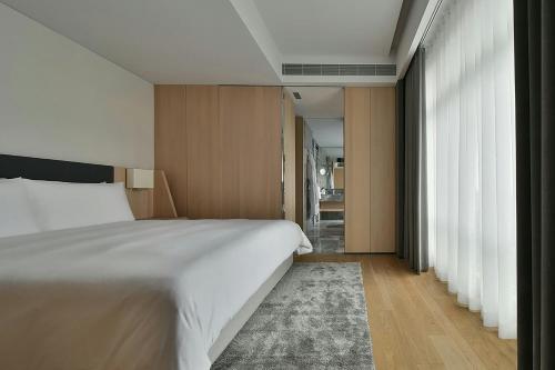 a bedroom with a large white bed and a rug at THE AMNIS, a Luxury Collection Hotel, Kaohsiung in Kaohsiung