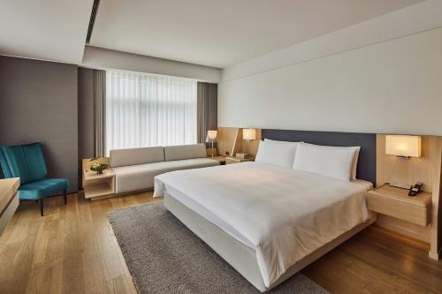 a hotel room with a large bed and a couch at THE AMNIS, a Luxury Collection Hotel, Kaohsiung in Kaohsiung