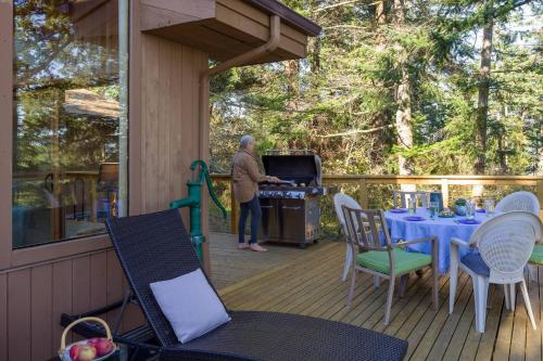 a man standing on a porch with a grill on a deck at Waterfront Privacy, Pet-friendly, Close To Trails in Olga
