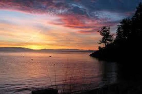 a sunset over a large body of water at Waterfront Privacy, Pet-friendly, Close To Trails in Olga