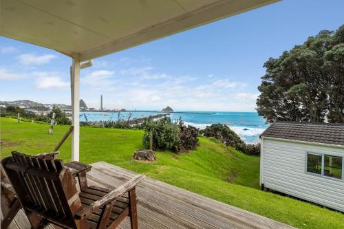 a porch with a bench and a view of the ocean at Belt Road Seaside Holiday Park in New Plymouth