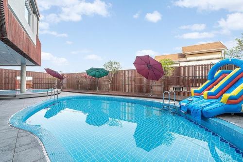 a swimming pool with chairs and umbrellas at Yeongdeok Hillington Hotel Resort Pension in Changsa-ri