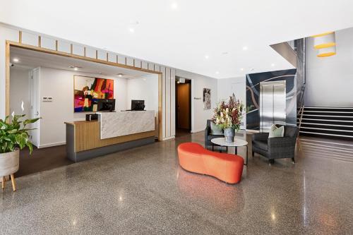 a living room with an orange chair and a table at Quarters at Flinders Hotel in Flinders