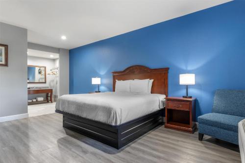 a bedroom with a bed and a blue wall at SureStay by Best Western McAlester in McAlester