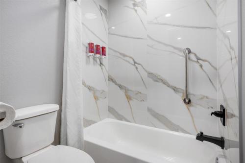 a bathroom with a white toilet and a shower at SureStay by Best Western McAlester in McAlester