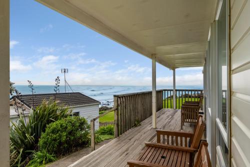 a porch with two benches and a view of the ocean at Belt Road Seaside Holiday Park in New Plymouth