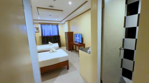 a small room with a bed and a television at Whiterock Beach Hotel and Waterpark in Subic