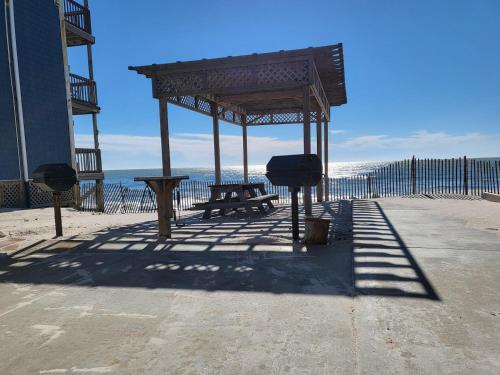 a picnic table and a bench on a beach at Beachfront Bungalow 124 in North Topsail Beach