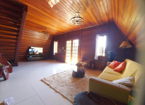 a living room with wooden ceilings and a couch at Sítio Vista Alegre in São Luiz do Paraitinga