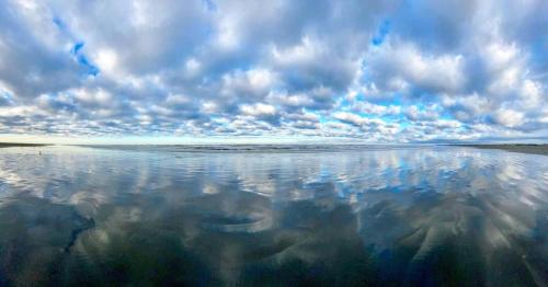 a reflection of a cloudy sky in the water at Tidal House #10 - Ocean Shores Chalet in Ocean Shores
