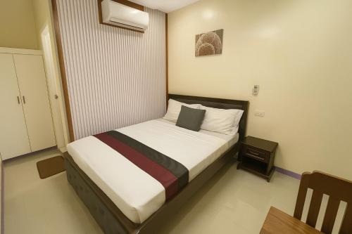 a small bedroom with a bed with white sheets at Home Stay Hotel in Canelar