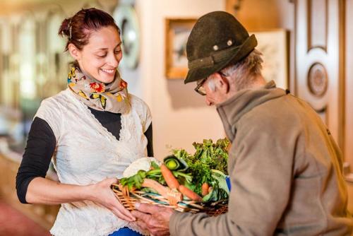 a man and a woman holding a basket of vegetables at Hotel Stefaner in Tires