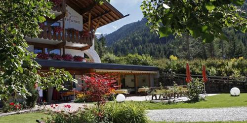 a building with a table and chairs in a garden at Hotel Stefaner in Tires