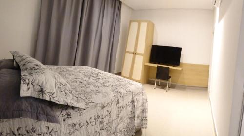 a bedroom with a bed and a flat screen tv at Apartamentos chácara com café da manhã incluso in Petrolina