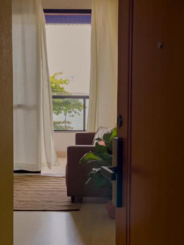 a living room with a couch and a window at Apê com vista para o mar e clima animado in Vitória