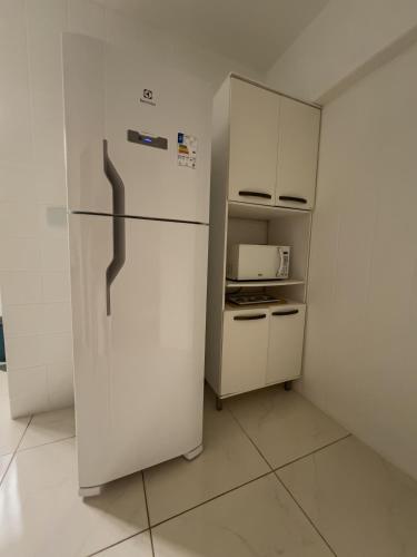a white refrigerator in a room with a kitchen at Apê com vista para o mar e clima animado in Vitória