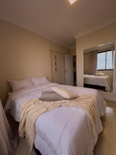 a bedroom with two beds with white sheets and a window at Apê com vista para o mar e clima animado in Vitória