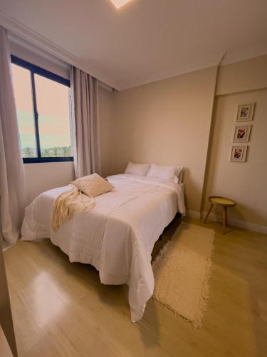 a bedroom with a large white bed with a window at Apê com vista para o mar e clima animado in Vitória