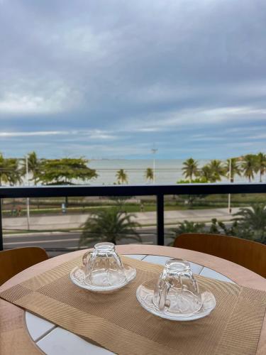 a table with two wine glasses on top of it at Apê com vista para o mar e clima animado in Vitória