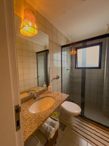 a bathroom with a sink and a toilet and a mirror at Apê com vista para o mar e clima animado in Vitória