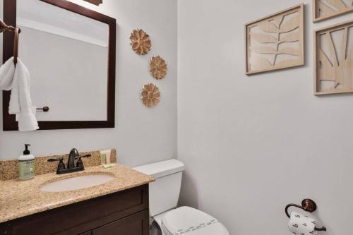 a bathroom with a sink and a mirror and a toilet at Kiss The Wave - Spacious 4br3ba, Wpoolhot Tub in Indian Harbour Beach