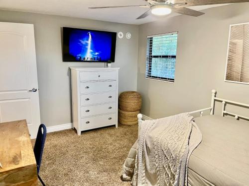 a bedroom with a bed and a tv on a wall at Kiss The Wave - Spacious 4br3ba, Wpoolhot Tub in Indian Harbour Beach