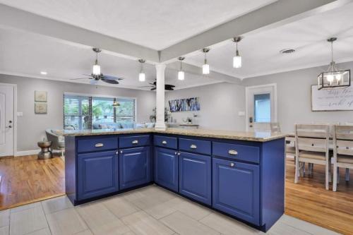 a kitchen with blue cabinets and a dining room at Kiss The Wave - Spacious 4br3ba, Wpoolhot Tub in Indian Harbour Beach