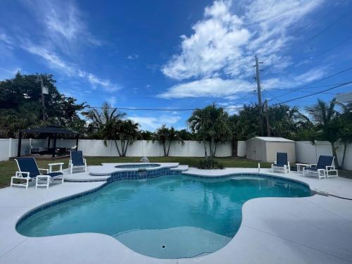 a large swimming pool with chairs at Kiss The Wave - Spacious 4br3ba, Wpoolhot Tub in Indian Harbour Beach