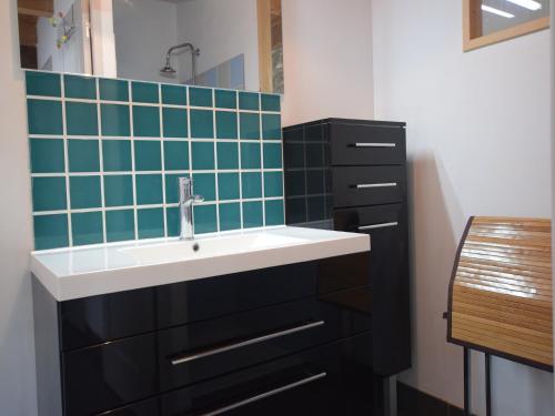 une salle de bain avec un lavabo et un mur carrelé vert dans l'établissement Cottage in Mirabel near Chauvet Cave, à Mirabel