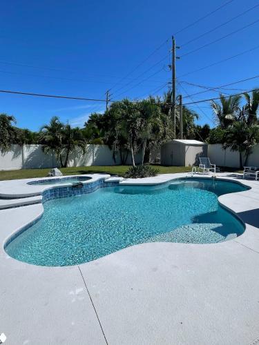 a swimming pool with blue water in a driveway at Kiss The Wave - Spacious 4br3ba, Wpoolhot Tub in Indian Harbour Beach