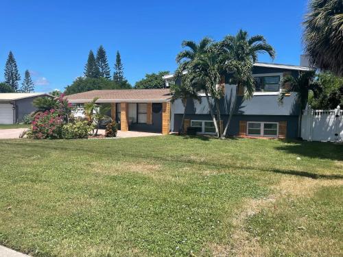 a house with a palm tree in a yard at Kiss The Wave - Spacious 4br3ba, Wpoolhot Tub in Indian Harbour Beach