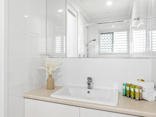a white bathroom with a sink and a mirror at Beachside Views 2 Bedroom Apartments Mooloolaba in Mooloolaba