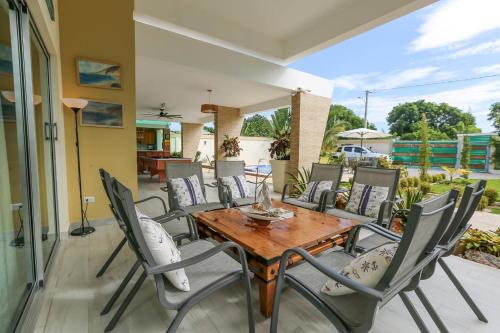 a patio with a wooden table and chairs at Villa Alida Nagua Pool Beach Dailymaid & Bbq in Matancita