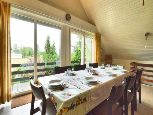 a dining room with a table and chairs and windows at Cozy Forest Chalet in Ovifat in Ovifat