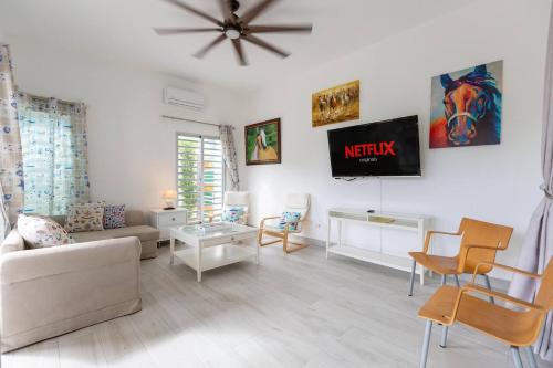 a living room with a couch and a tv on the wall at Villa Alida Nagua Pool Beach Dailymaid & Bbq in Matancita