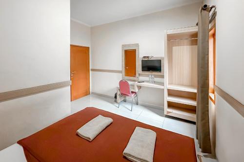 a small room with a red rug and a desk at Hotel Cemara Hijau Mitra RedDoorz in Bandung