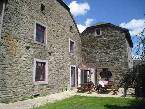 two people sitting at a table outside of a stone building at Spacious Farmhouse, Libramont in Libramont