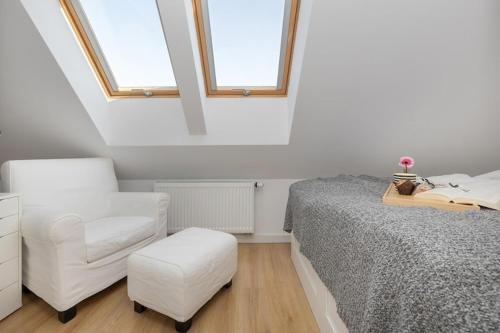 a bedroom with a bed and a chair and windows at Holiday home, 3 bedrooms, private garden in Trzęsacz