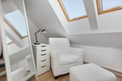a bedroom with a white chair and a mirror at Holiday home, 3 bedrooms, private garden in Trzęsacz