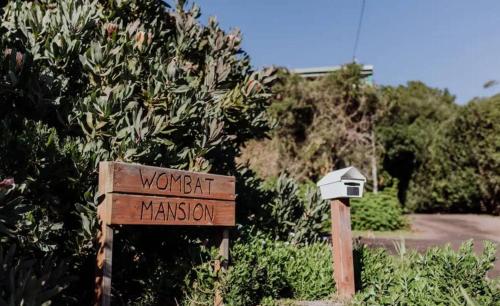 a sign in front of a bush with a street sign at Wombat Mansion in Binalong Bay