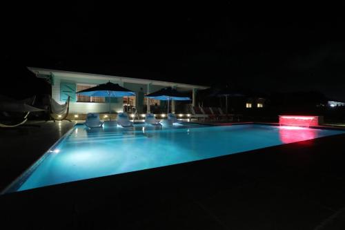 a swimming pool at night with chairs and umbrellas at Oceanfront Resort-Style Oasis -Private Pool & Car in Grand Turk