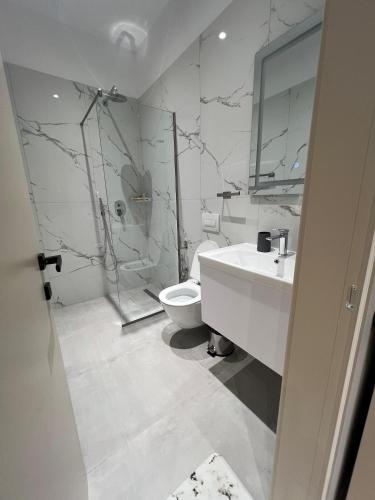 a white bathroom with a toilet and a sink at Vila Serenita in Vlorë