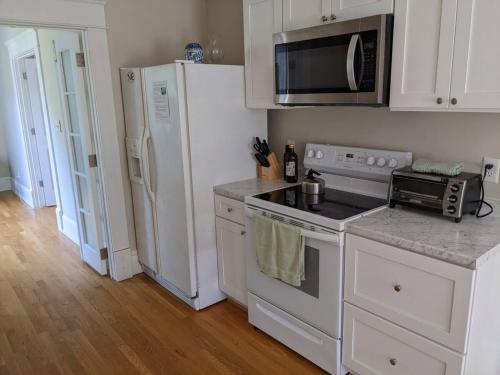 a white kitchen with a stove and a refrigerator at Luxurious 1BR in Grand Old Home in Durham