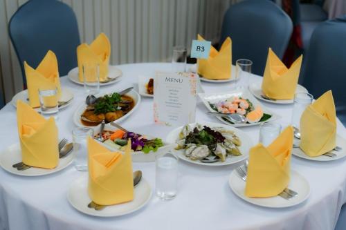 a table with plates of food with yellow napkins at Lailaresidence in Yala