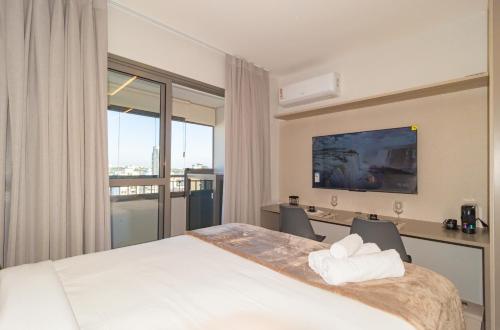 a hotel room with a bed and a desk and a window at Prime Grand Vitrali Moema in Sao Paulo