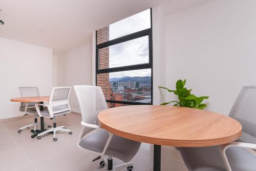 an office with two tables and chairs and a window at Metropolitan Living by HOUSY in Medellín