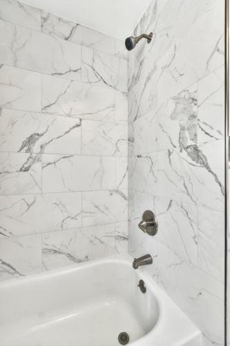 a white bathroom with a white tub and marble walls at Treasure home in St-Pete Beach in St. Pete Beach