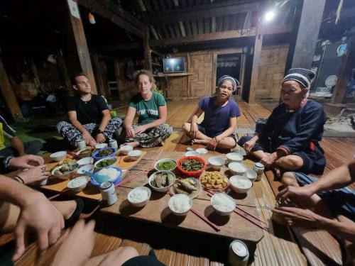 a group of people sitting around a table with food at Nậm Lỳ Retreat in Ha Giang