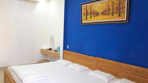 a blue room with a bed and a painting on the wall at Khoi Nguon in Da Nang
